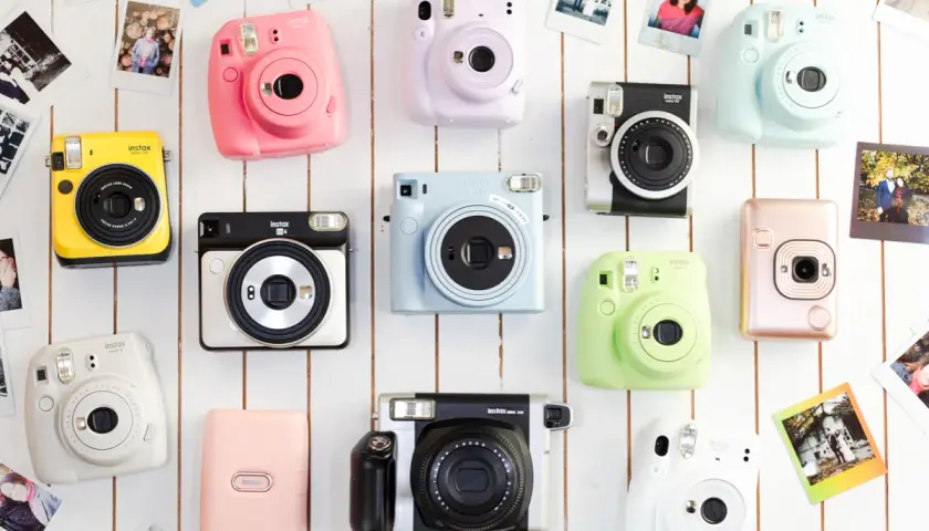 Kolekcja kolorowych aparatów do fotografii natychmiastowej Instax, ułożonych na białym tle.