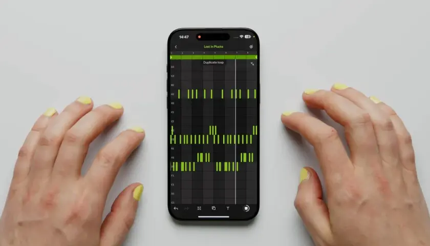 Hände mit gelbem Nagellack steuern eine Musik-App auf dem Handy. Grüne Balken zeigen einen Ableton Note-Beat.