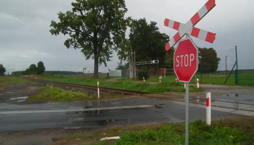 Wielotorowy przejazd kolejowy z czerwonym znakiem STOP i rogatkami.