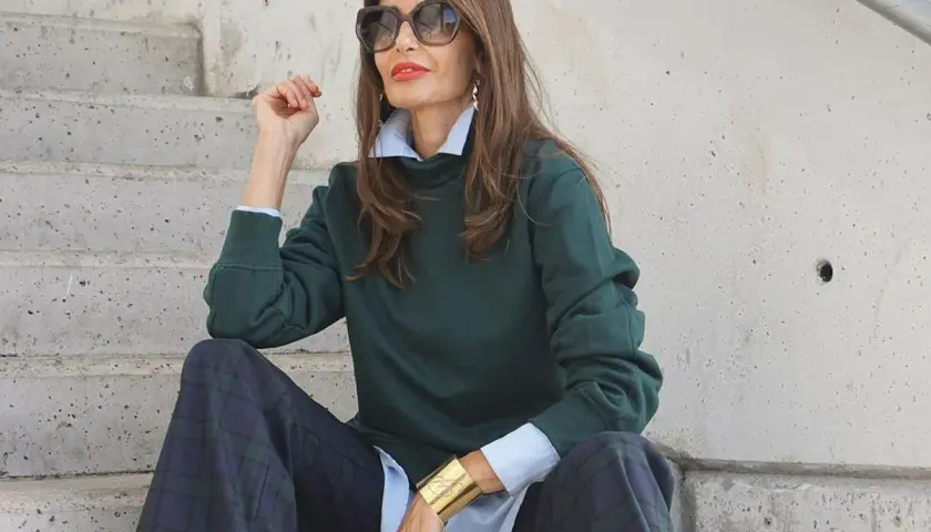 Elegancka kobieta po 50-tce w zielonym swetrze i kratkowych spodniach. Stylowe moda po 50-tce stylizacje.