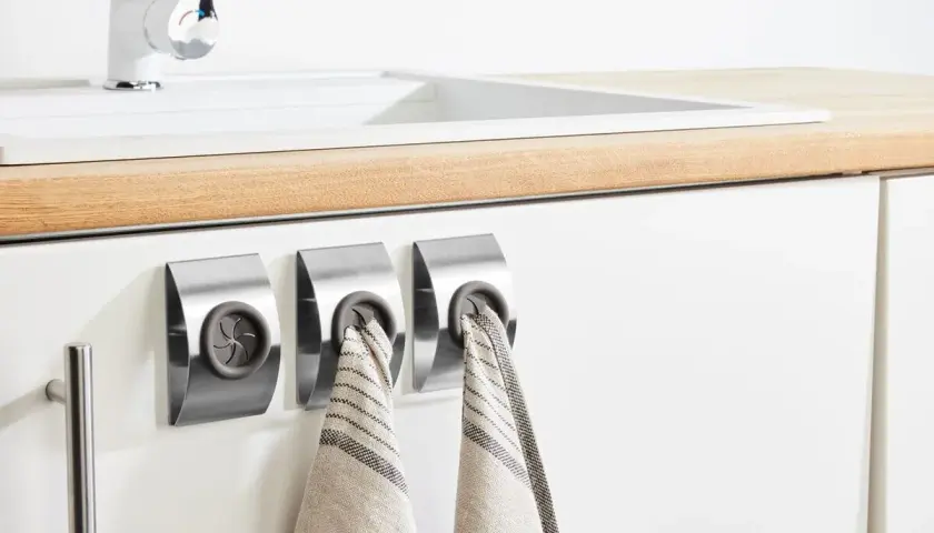 Colgadores de trapos modernos de acero inoxidable junto a un fregadero blanco.