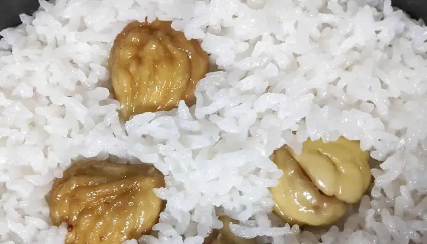 A close-up of fluffy white rice with sweet, glazed chestnuts scattered throughout. This chestnut rice looks delicious and comforting.