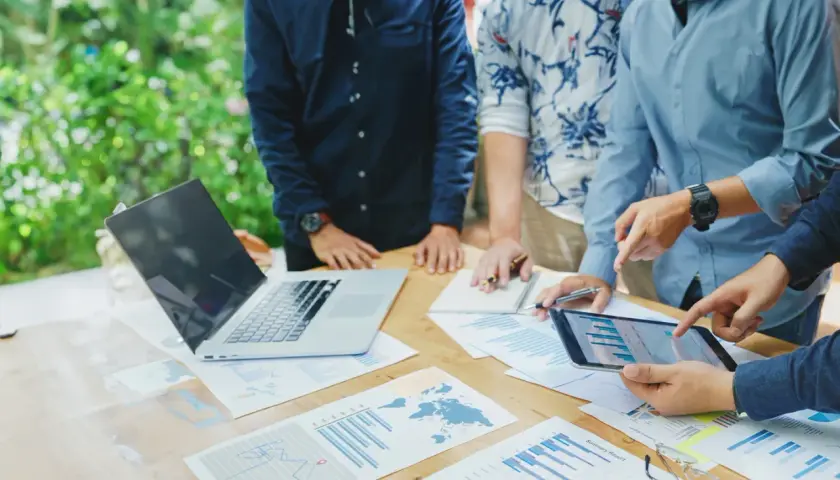 Team discute grafici e dati su un tavolo all'aperto, pianificando i loro buoni propositi per il futuro.