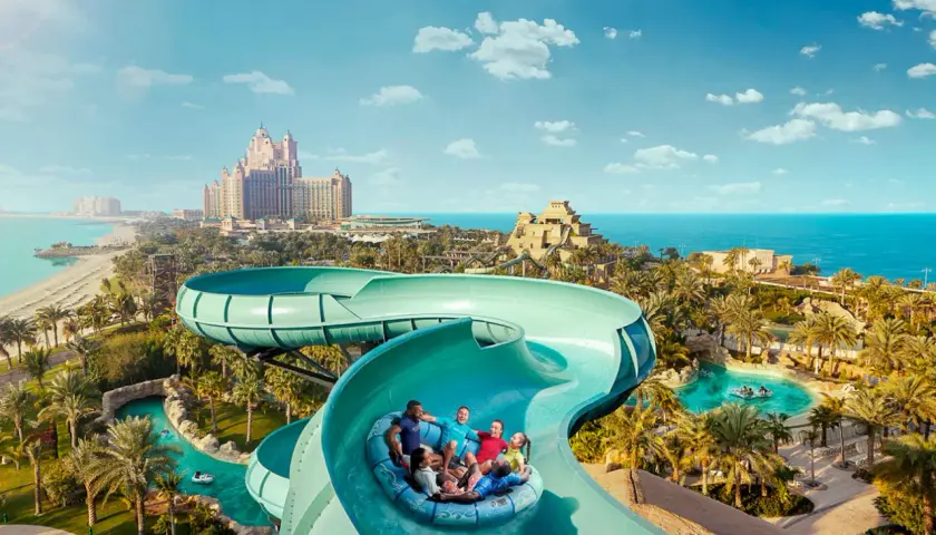 Familie hat Spaß im Dubai Wasserpark auf einer Rutsche, mit dem Atlantis Hotel im Hintergrund.