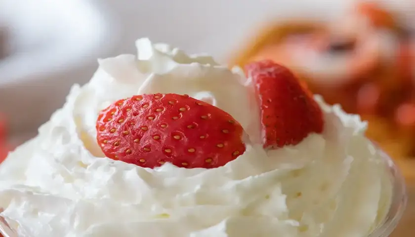 Chantilly aérienne garnie de fraises fraîches. Une invitation à découvrir comment faire de la chantilly maison pour un dessert parfait.