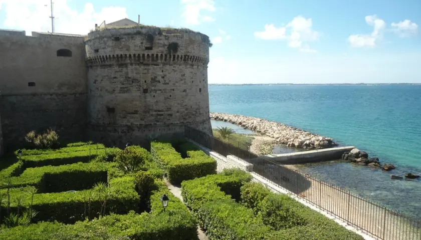 Castello Aragonese e giardini curati, un'idea di cosa vedere a Taranto in mezza giornata, con il mare azzurro sullo sfondo.