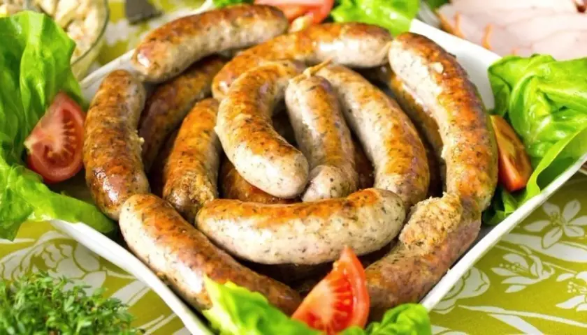 Pyszna biała kiełbasa surowa, idealna do pieczenia. Podana z sałatą i pomidorem.