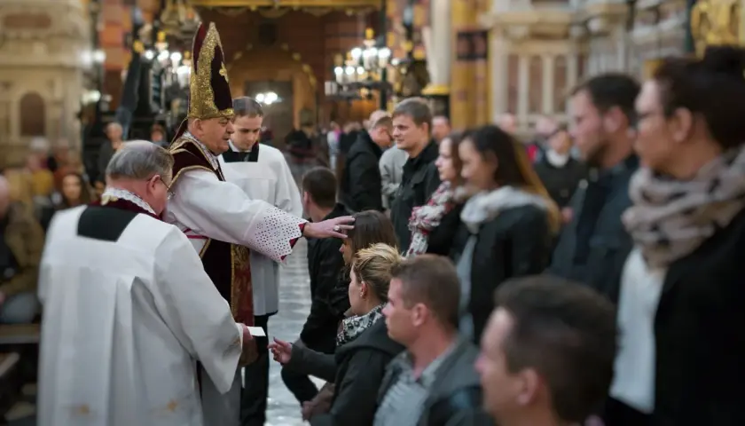 Biskup udziela sakramentu bierzmowania. Czy świadek do bierzmowania musi być pełnoletni? Wierni czekają w kościele.