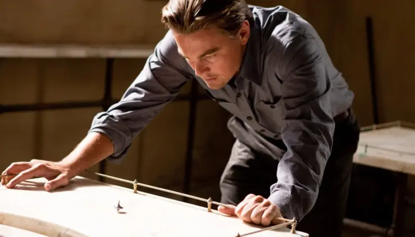 Leonardo DiCaprio pochyla się nad stołem, obserwując wirujący bączek. Czy to jego sposób na zrozumienie, czym jest incepcja?