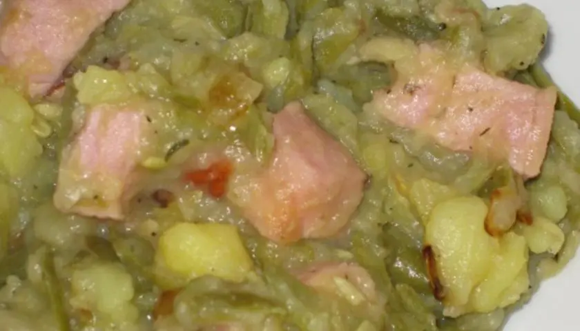 Ein herzhafter saure bohnen eintopf mit Kartoffeln und rosa Speckstücken, dampfend und bereit zum Genießen.