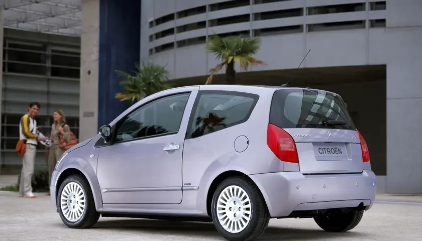 Jasnoszary Citroën C2 z parą na tle nowoczesnego budynku.