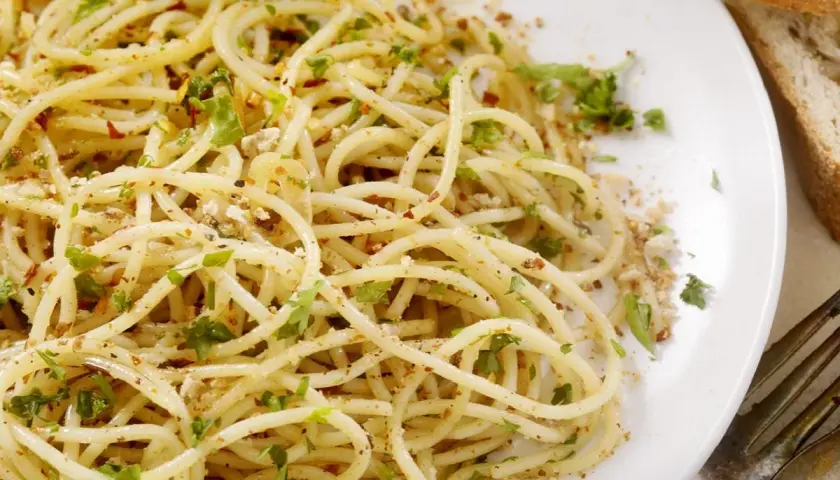 Un piatto di spaghetti alla carrettiera, conditi con aglio, olio, peperoncino e prezzemolo fresco, con una spolverata di pangrattato tostato.