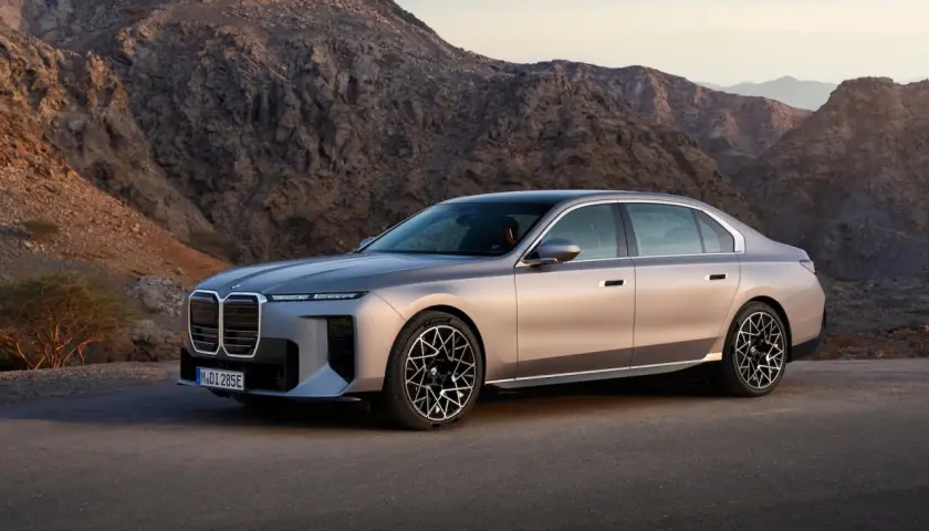 Luksusowy sedan BMW i7, lider rankingu samochodów elektrycznych, na tle surowych górskich krajobrazów.