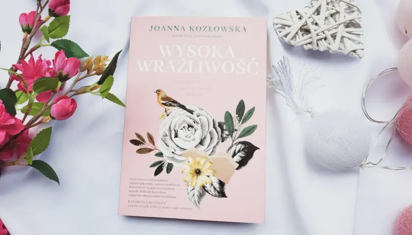 Różowa okładka książki "Wysoka wrażliwość" z motywem kwiatów i ptaszka, otoczona dekoracjami.