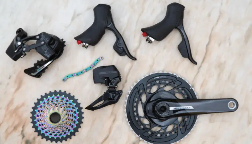 SRAM news: A new Force AXS groupset with rainbow cassette, crankset, derailleurs, and shifters laid out on a marble surface.