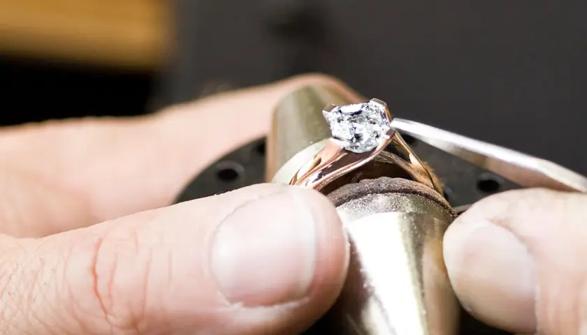 Ein Juwelier setzt einen funkelnden Diamanten, einen kostbaren Edelstein, in eine Ringschiene ein.