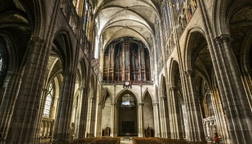 Wnętrze katedry Saint-Denis z organami i witrażami. Puste ławki czekają na wiernych w tej zabytkowej budowli.