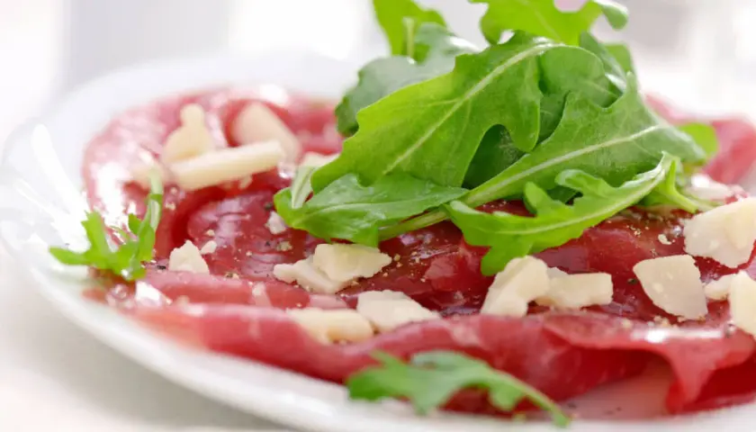 Cienkie plastry wołowiny z rukolą i parmezanem, skropione pysznym sosem do carpaccio.