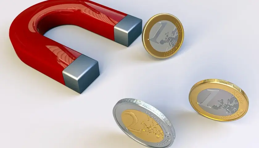 Czerwony magnes podkowowy przyciąga monety euro.