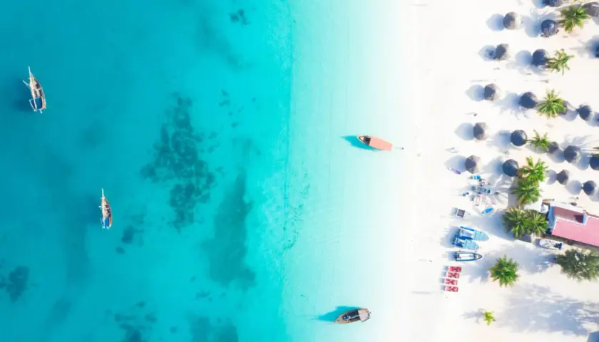 Rajska plaża na Zanzibarze, gdzie turkusowa woda i biały piasek tworzą idealne tło dla tradycyjnych łodzi. Można tu poczuć atmosferę wakacji, marząc o przygodach i wymieniając się wrażeniami, jakby to była lokalna waluta.