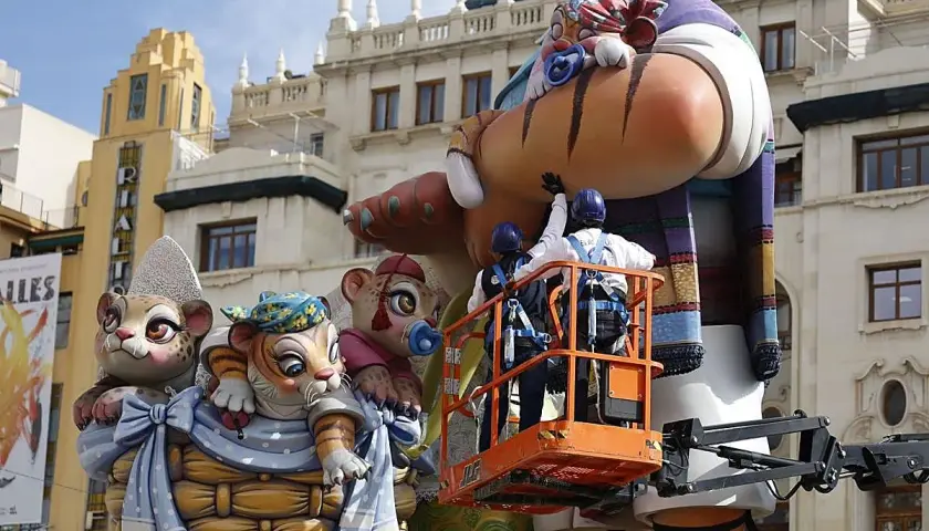 Dos operarios en una grúa trabajan en una falla gigante con figuras de animales. Se acerca el momento cuando es la planta.