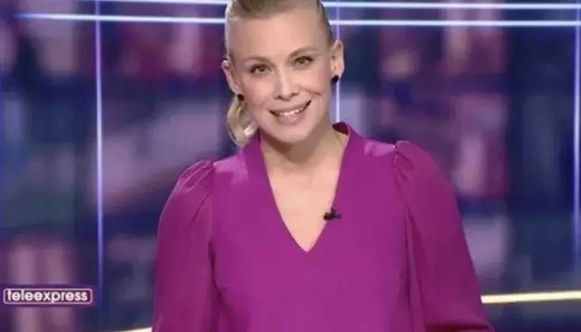 Aleksandra Kostrzewska uśmiecha się do kamery w fioletowej bluzce. W tle logo "teleexpress".