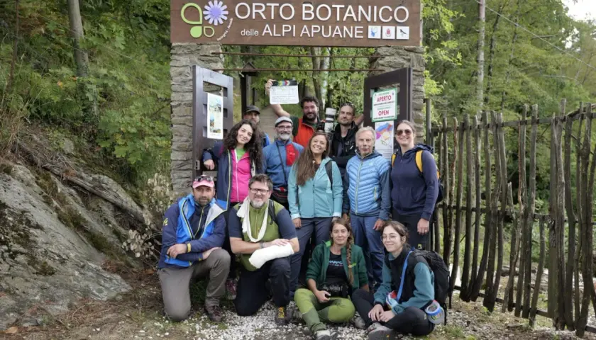 Gruppo di escursionisti posa davanti all'Orto Botanico delle Alpi Apuane. Un uomo tiene in mano una ciak.