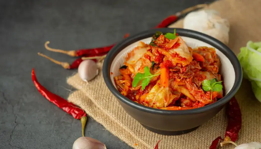 Miseczka z kimchi, obok suszone papryczki chili i czosnek.
