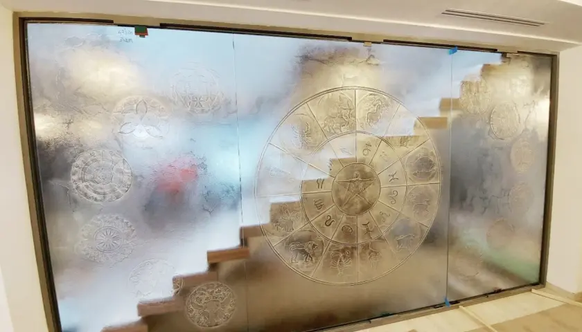 Witrażowe szkło strukturalne z motywem zodiaku i mandali. Schody widoczne przez matowe szkło.