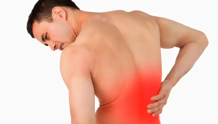 Hombre con dolor lumbar izquierdo, con la mano en la zona afectada y expresión de sufrimiento.