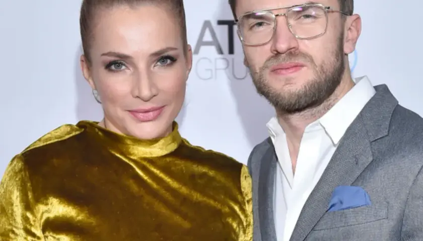Anna Dereszowska i Maksymilian Duniak na ściance. Ona w złotej sukni, on w szarym garniturze.