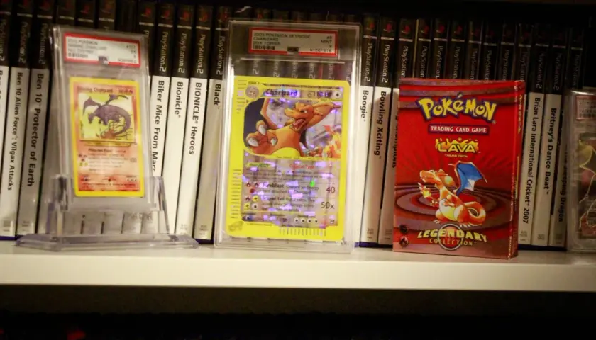 Pokémon-kort och en Pokémon-kortlek på en hylla, bland andra samlarobjekt.