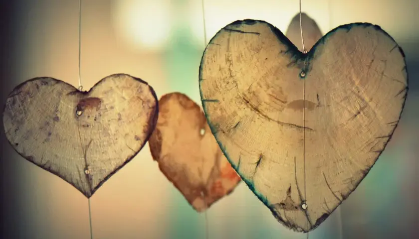 Holzherzen hängen an dünnen Fäden. Sie erinnern an die wahre agape bedeutung: bedingungslose Liebe, die wächst und Bestand hat.