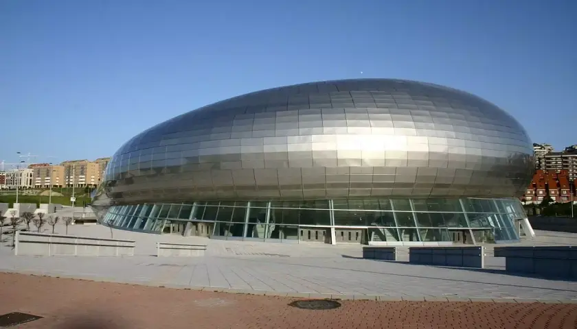 El moderno Palacio de Deportes Santander, con su diseño futurista y su cubierta plateada, se alza bajo un cielo azul.