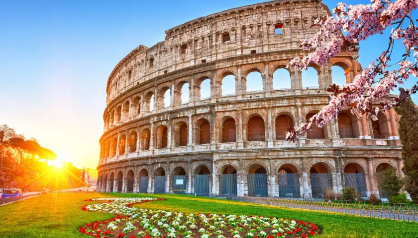 Colosseo illuminato dal sole, con fiori primaverili. Ideale per un soggiorno di costo metro Roma 2 giorni.