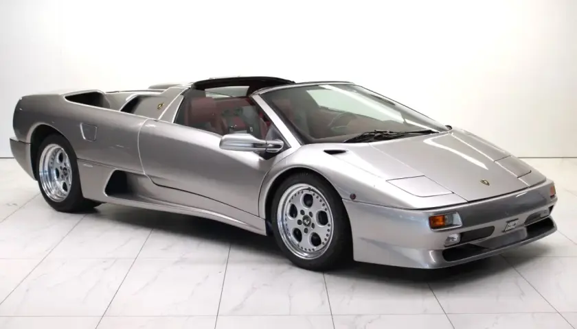 Srebrny kabriolet Lamborghini Diablo z czerwonym wnętrzem, zaparkowany na białej, marmurowej podłodze.