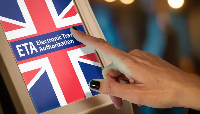 Dłoń dotyka ekranu z flagą Wielkiej Brytanii i napisem ETA Electronic Travel Authorization.