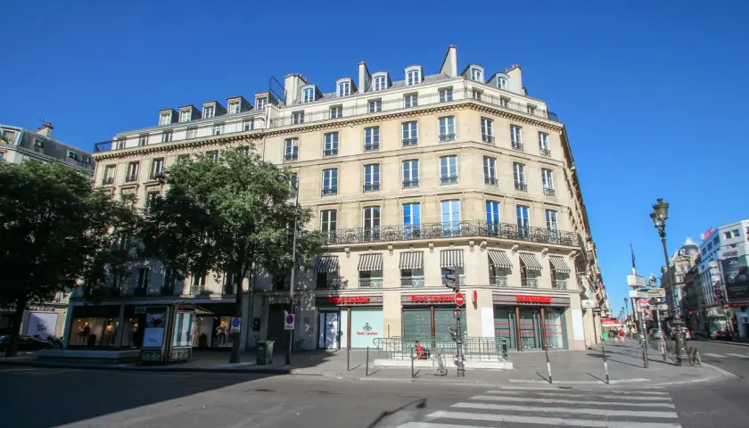 Elegancka kamienica przy rue de Rivoli w Paryżu, z markizami nad oknami i sklepem Foot Locker na parterze.