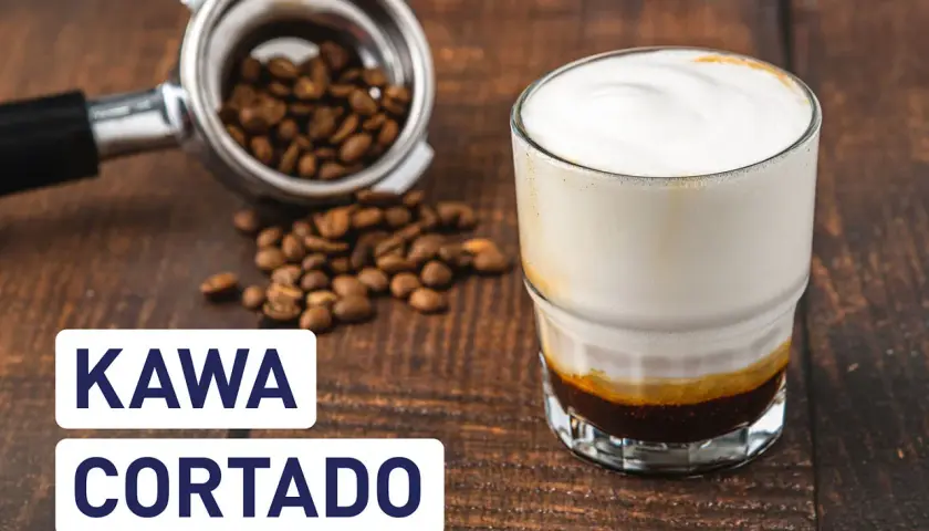 Kawa cortado z mleczną pianką, obok portafiltr z ziarnami kawy. Idealna na poranek.
