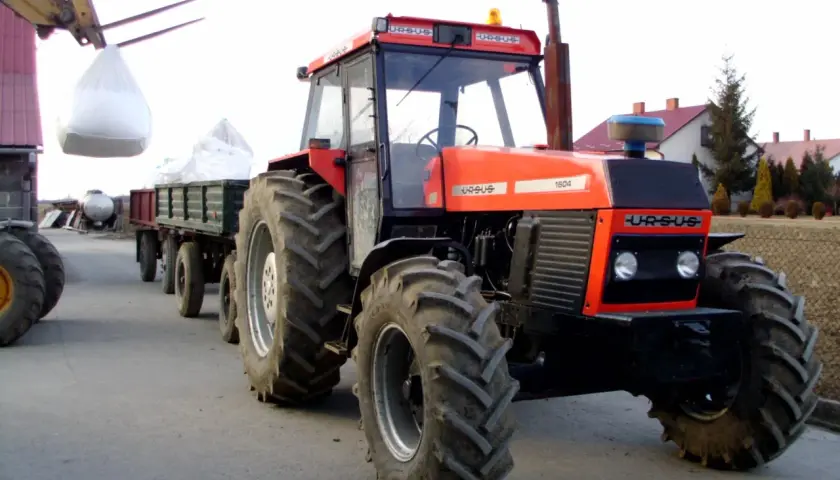 Czerwony Ursus 1604 z przyczepą załadowaną workami, gotowy do pracy na gospodarstwie.