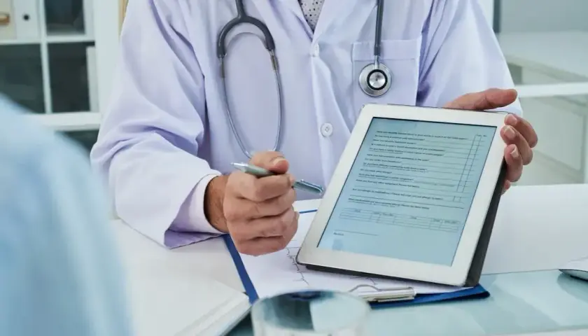Medico con stetoscopio mostra un modulo su tablet, forse per una nuova unità di degenza.