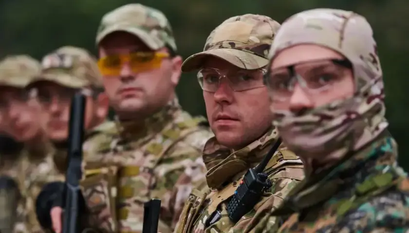 Grupa żołnierzy w kamuflażu, jeden z nich to starszy szeregowy specjalista, gotowi do akcji.