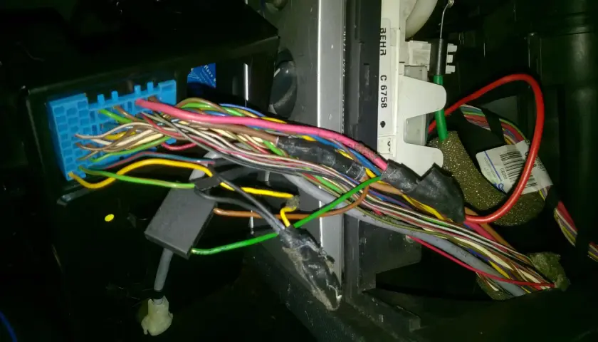 Plątanina przewodów w Opel Meriva, widoczny niebieski konektor i fragmenty instalacji elektrycznej, być może związane z lokalizacją bezpieczników.