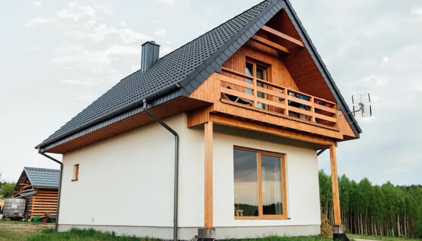 Nowoczesny dom kanadyjski, białe ściany, drewniana weranda i dach. Projekty domów tego typu są popularne.