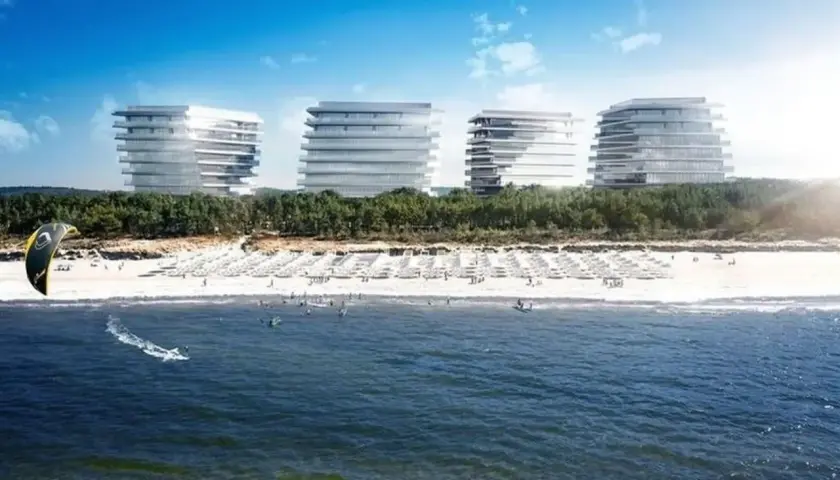 Nowoczesne budynki nad plażą w Międzyzdrojach, gdzie widać kitesurfera na falach.