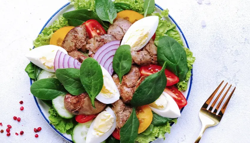 Salade Landaise appétissante avec foies de volaille, œufs durs, tomates, oignons rouges et légumes verts. Quel vin avec une salade landaise ? Un vin blanc sec et fruité.