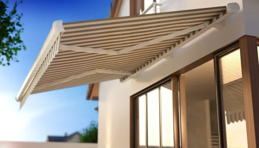 Gestreifte Markise über einer Terrassentür. Perfekt, um sie im Sommer zu reinigen und Schatten zu spenden.
