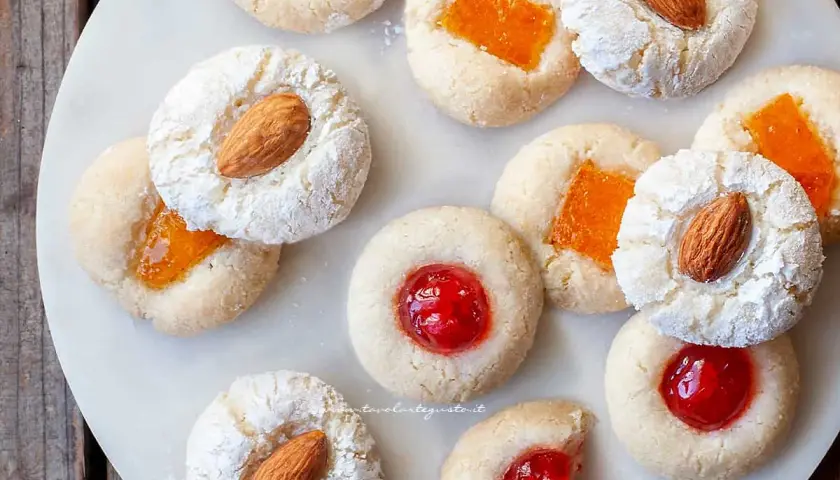 Biscotti con mandorle e marmellata, alcuni spolverati di zucchero a velo, ricordano un delizioso sorbetto alla mandorla.