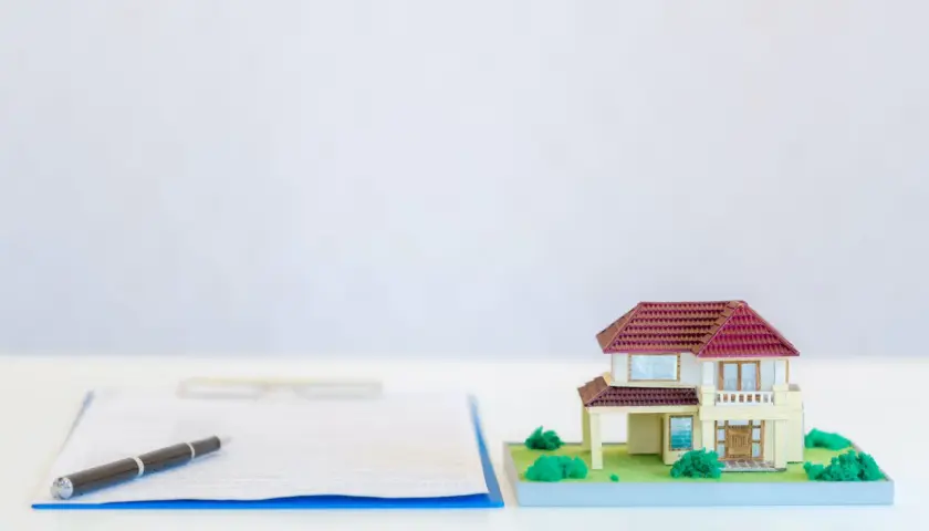 Wniosek KW-wpis wzór wypełnienia spadek. Miniatura domu obok dokumentów i długopisu sugeruje formalności związane z dziedziczeniem nieruchomości.