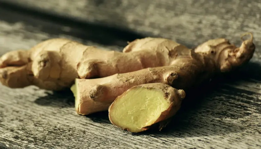 Raíces de jengibre fresco sobre madera, listas para explorar sus usos del jengibre en la cocina, aportando sabor y aroma a tus platos.